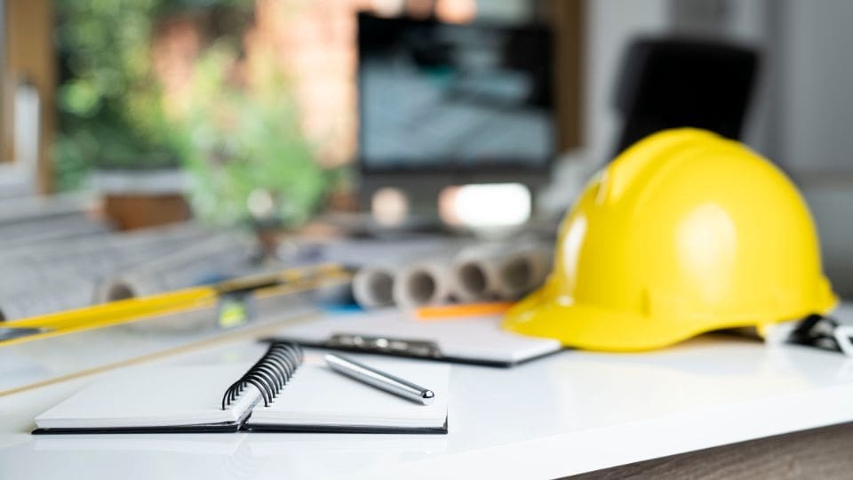 A Yellow Hard Hat And Pen On A White Table