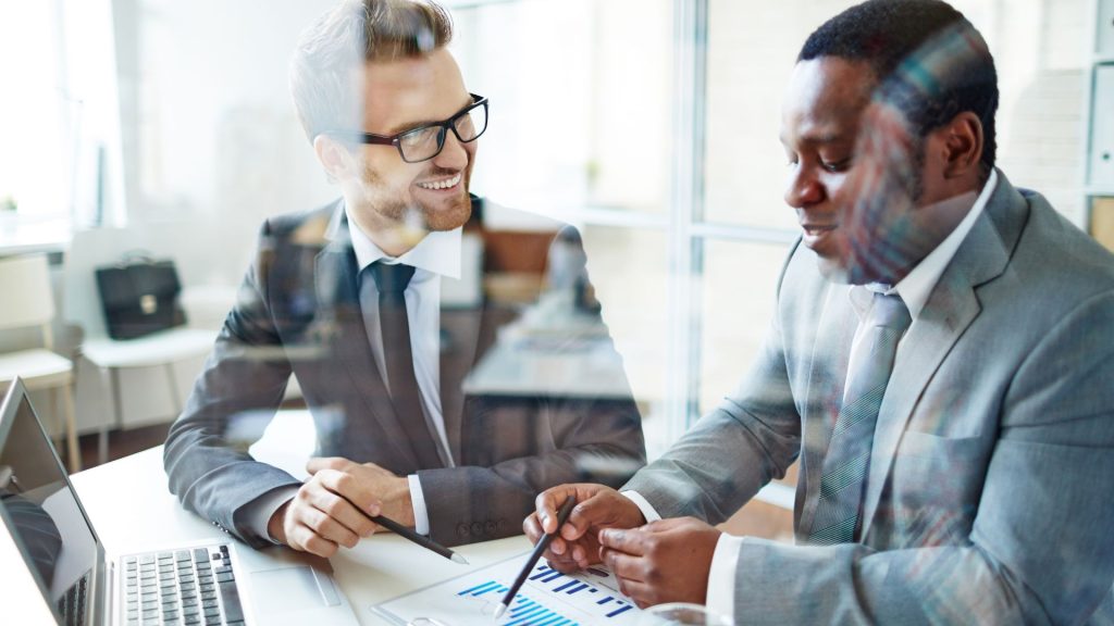 Insurance Advisor Explaining Coverage To Client At Office Desk